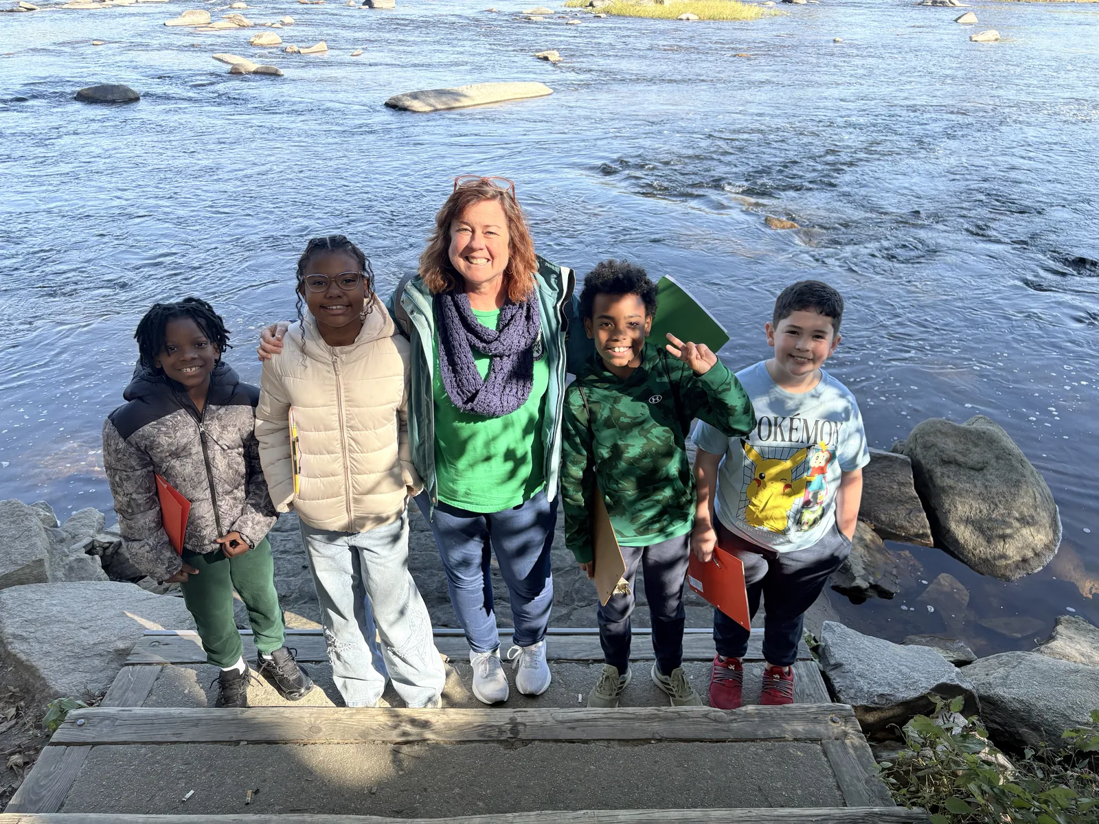 Laurel students and their teacher standing together on the rocks beside the James River