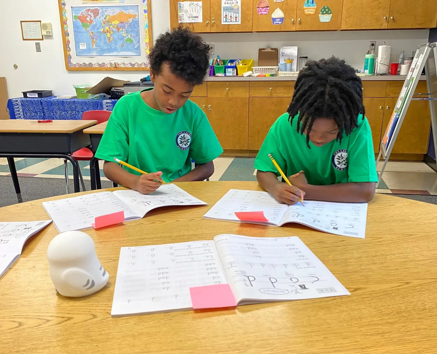 Two Laurel students working with books and written activities at a classroom table