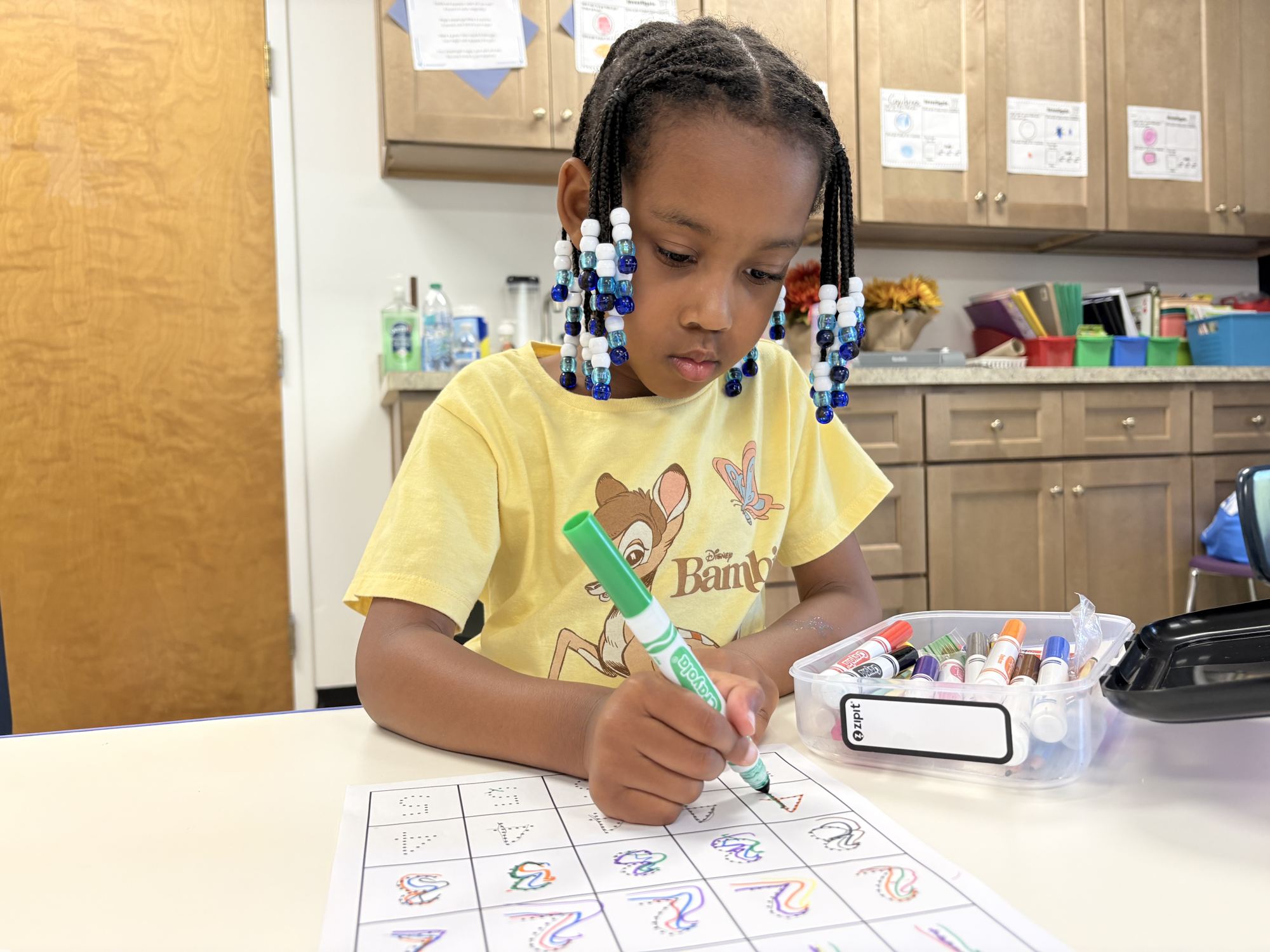 A Laurel student practicing letter formation with a marker