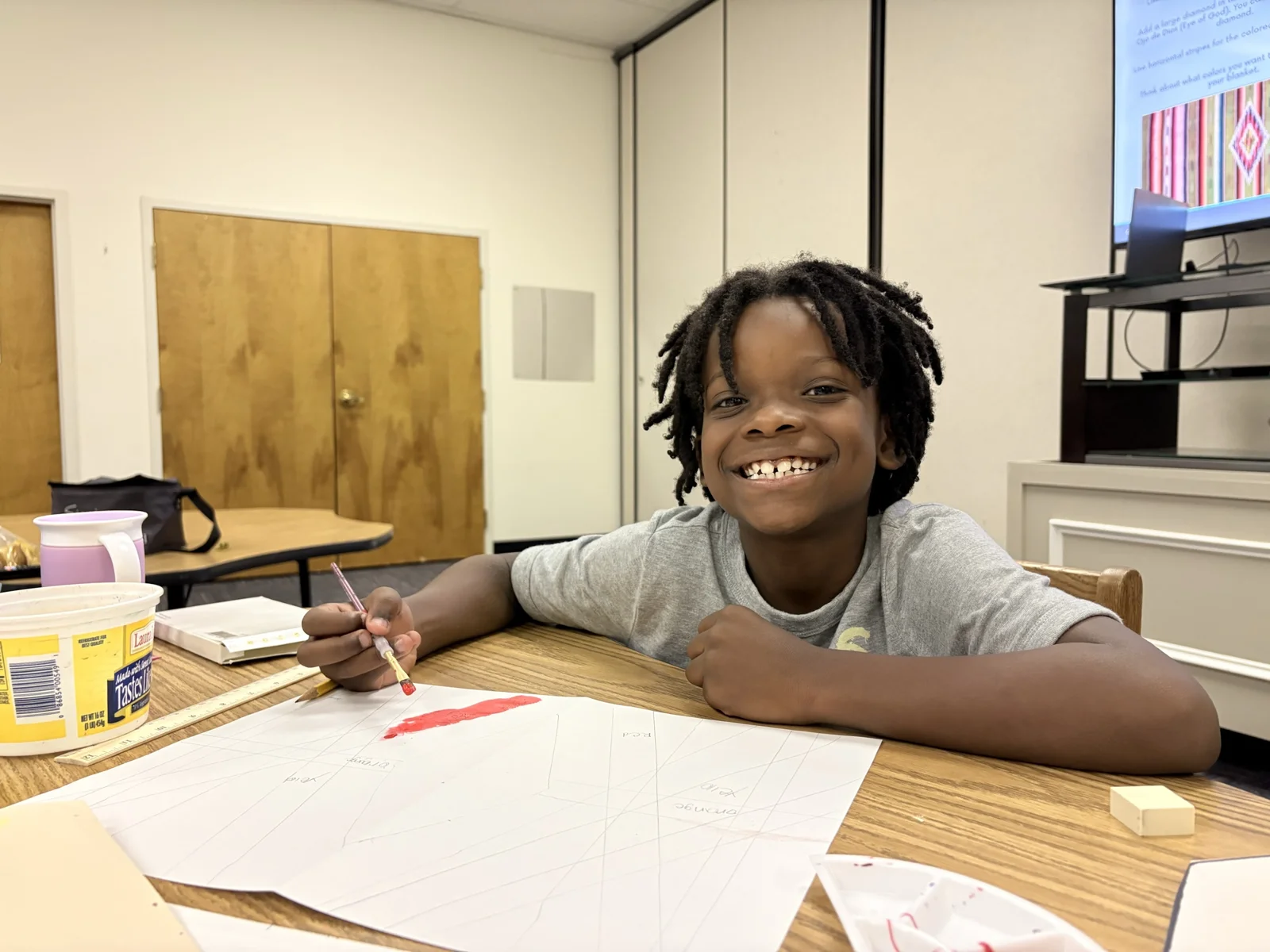 A Laurel student smiling at his desk with pencil and paper