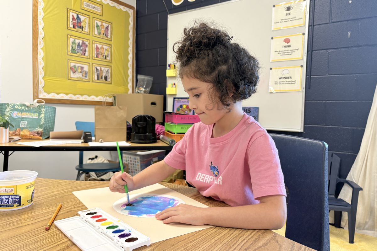 A Laurel student painting with watercolors at a classroom table