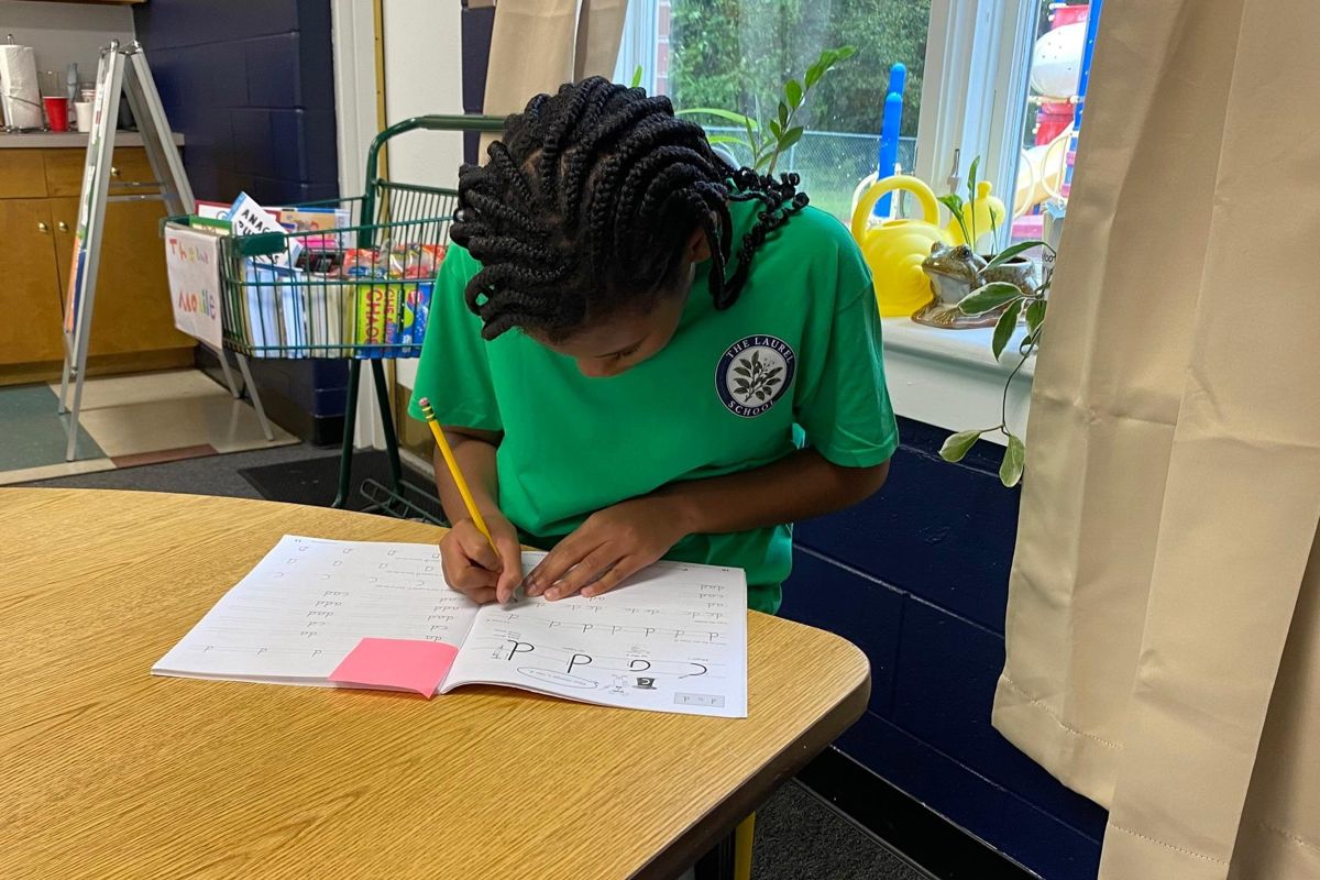A Lower Elementary student concentrating on handwriting practice at her desk