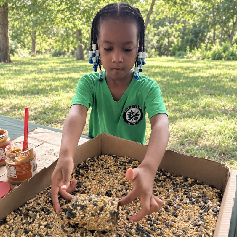 A Laurel student pressing seed into a homemade bird feeder outdoors