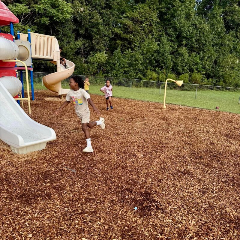 Laurel students racing across the mulched playground on a sunny afternoon